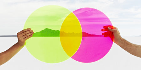 Two hands holding colored circles in landscape.